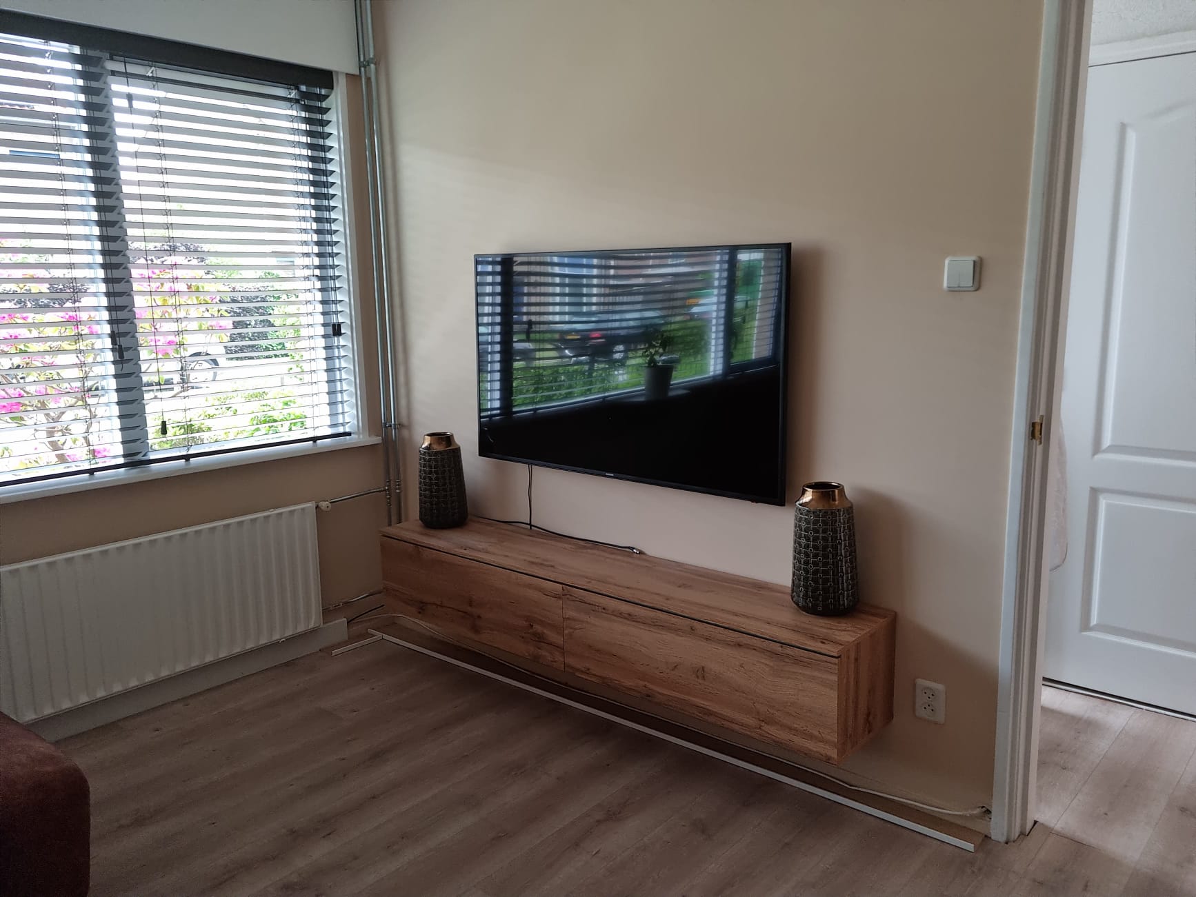 Woonkamerhoek in zacht crème met wandmeubel en tv aan de muur