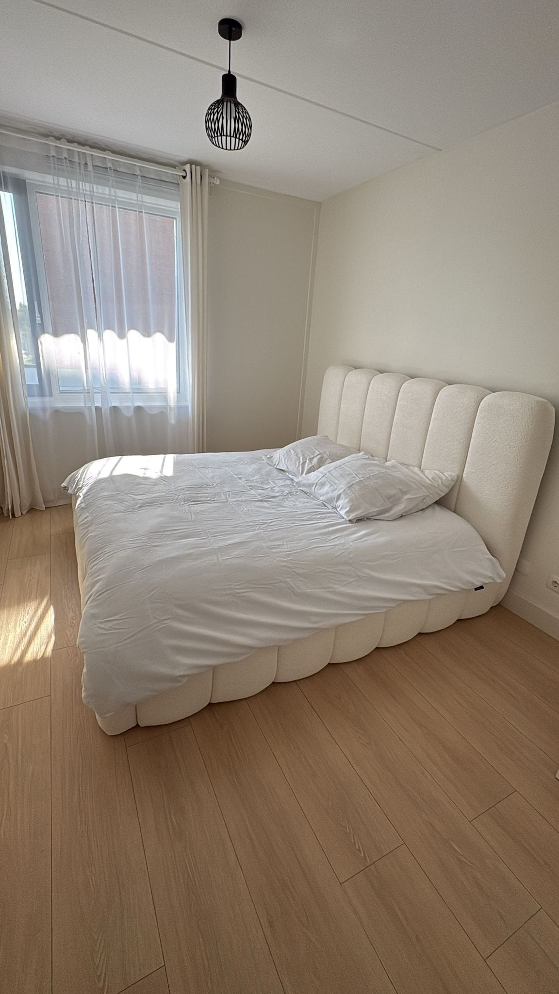 Slaapkamer in warm gebroken wit, met daglicht over de muur