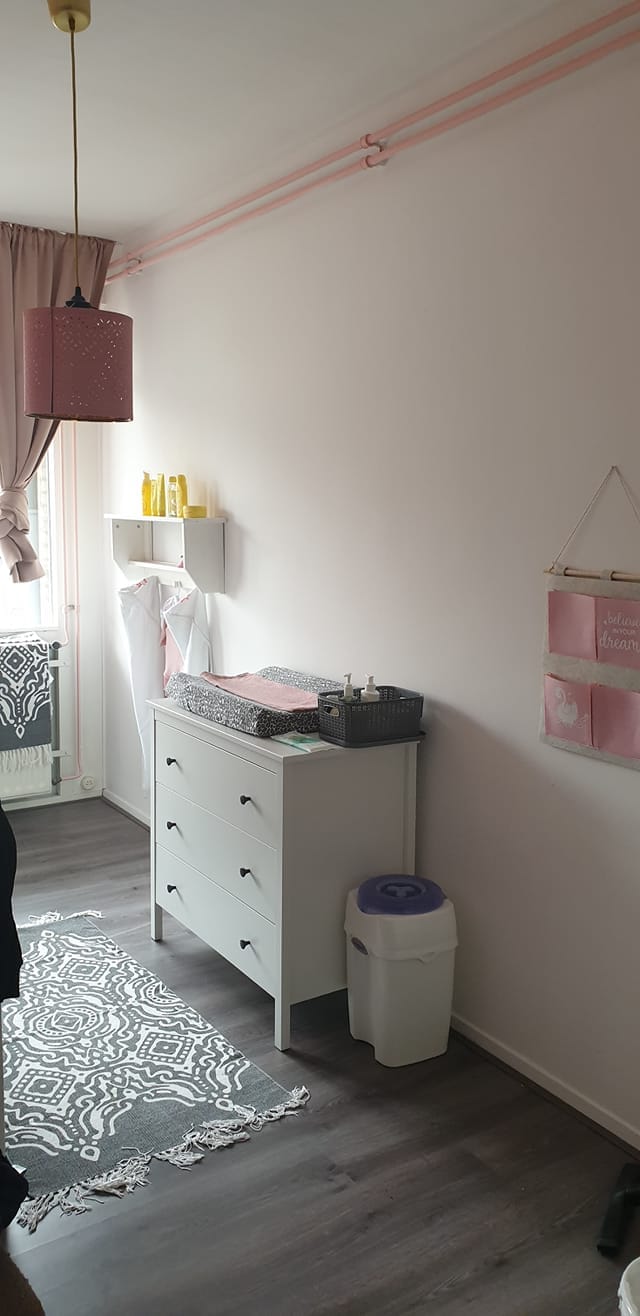 Babykamer in zacht wit met de leidingen langs het plafond in roze meegeschilderd